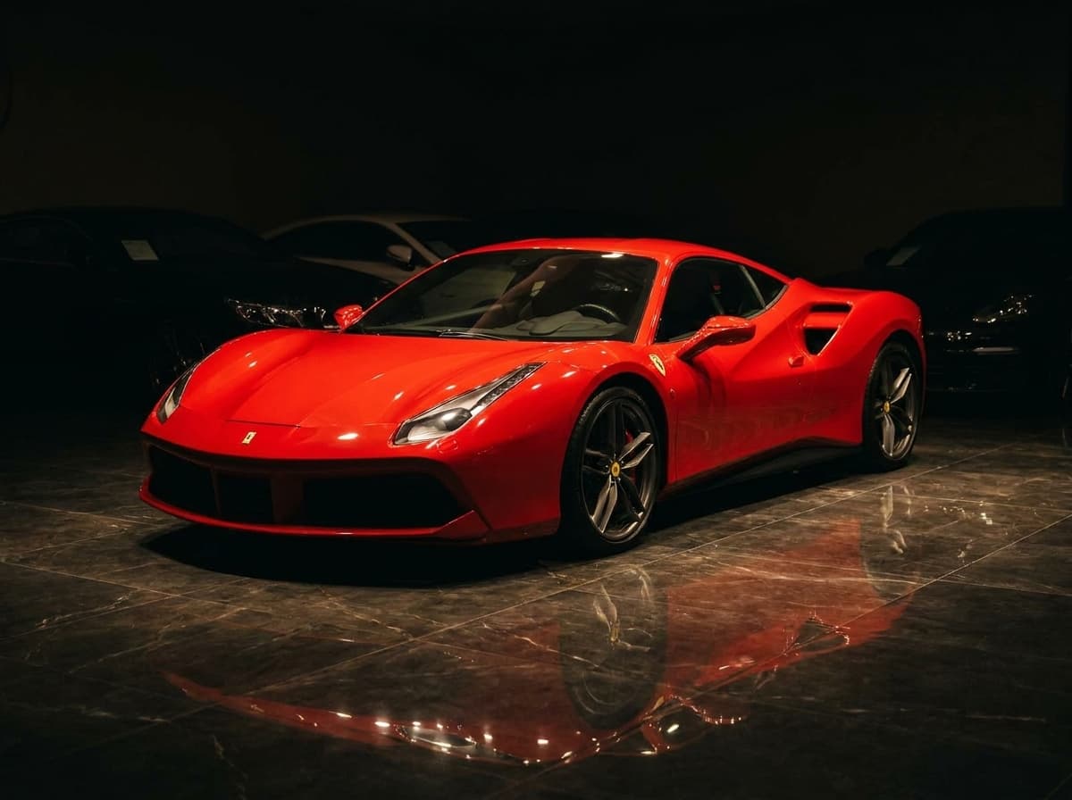 Roter Ferrari 488 unter dem Lichtkegel im nächtlichen Showroom von Sternenfeld Autocenter, Birsfelden